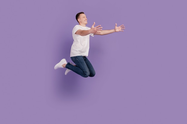 Retrato de hombre deportivo saltar las manos atrapan el espacio vacío sobre fondo violeta