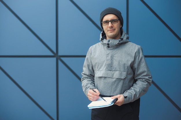 Retrato de un hombre con un diario de pie contra la pared