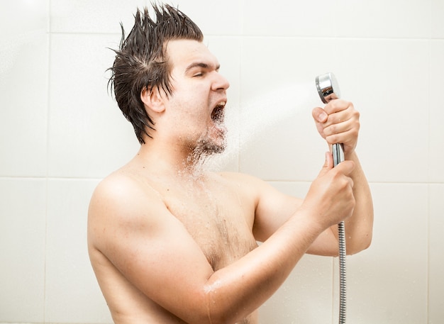 Retrato de hombre divertido cantando en la ducha