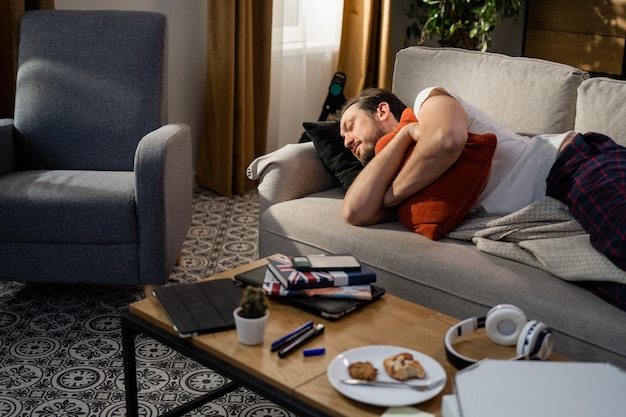 Retrato de un hombre dormido abrazando una almohada naranja contra su pecho el chico sonriente está soñando