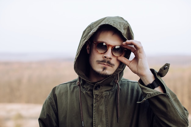 Foto retrato de un hombre elegante con bigote y barba en gafas de sol en las montañas