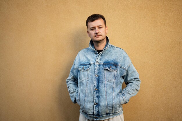 Retrato de hombre elegante con chaqueta de jeans contra la pared amarilla