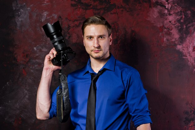 Retrato de hombre elegante fotógrafo profesional con cámara, usar en camisa azul y corbata.