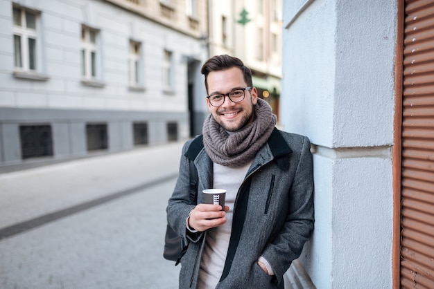 Retrato de un hombre elegante con una taza de café en calle de la ciudad.