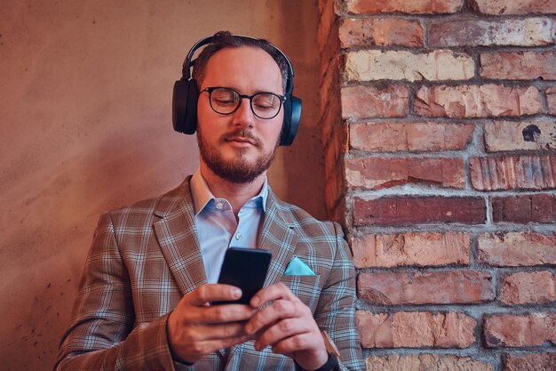 Retrato de un hombre elegante con traje de franela y gafas escuchando