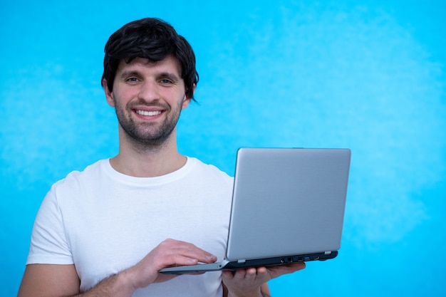 Retrato de un hombre emocionado sosteniendo una computadora portátil y celebrando el éxito