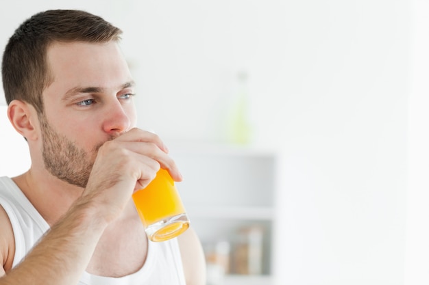 Retrato de un hombre encantado de beber jugo de naranja