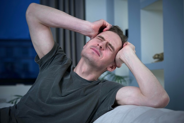 Retrato de un hombre enfermo, enfermo, poco saludable, joven, deprimido, triste, frustrado, molesto, el hombre está sufriendo debido a una tragedia, drama, dolor de cabeza o migraña. Se siente mal, mal, depresión, desesperación, dolor, concepto