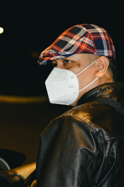 Retrato de un hombre enmascarado sentado en una motocicleta en la calle por la noche