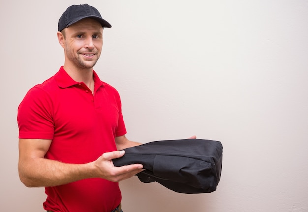 Retrato del hombre de entrega que sostiene la pizza en bolso termal