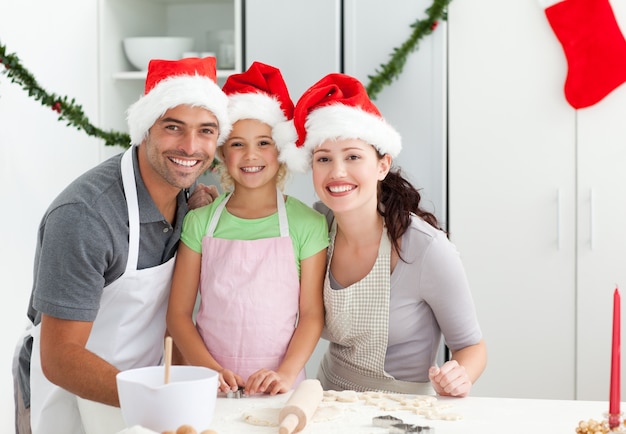 Retrato de un hombre con esposa e hija cocinando galletas de Navidad