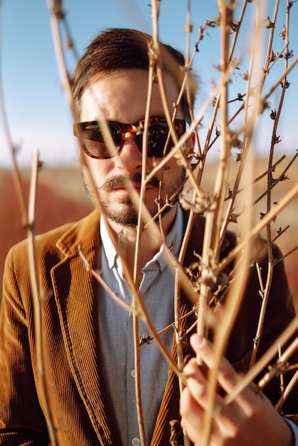 Retrato de hombre de estilo en paisaje de primavera Guapo hipster con gafas en día soleado