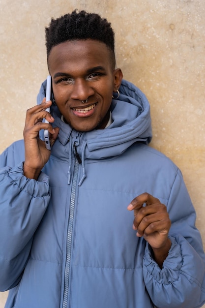 Retrato de un hombre de etnia negra con un teléfono y una chaqueta azul sobre un fondo amarillo hablando por teléfono