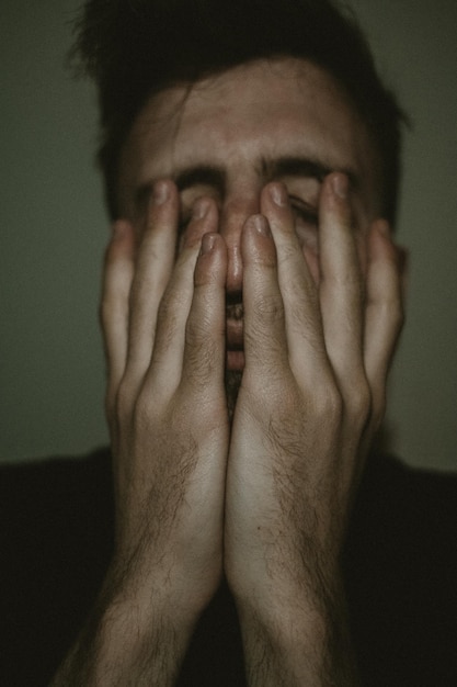 Foto retrato de un hombre europeo con la mano cubriendo la cara y pensando en un hombre con camisa que parece preocupado