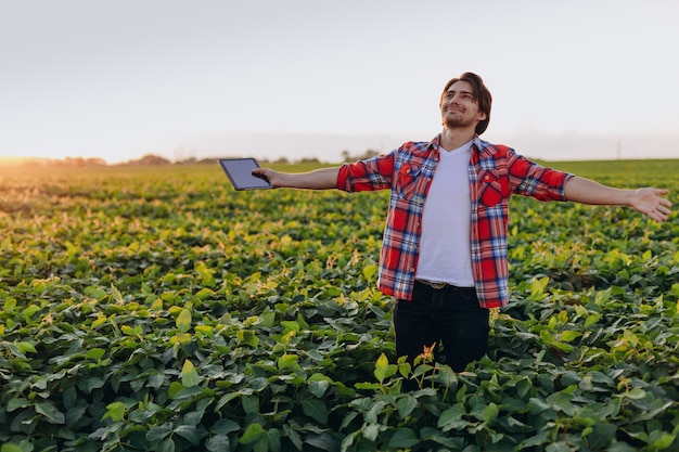 Retrato de hombre feliz agrónomo de pie en un campo con las manos separadas