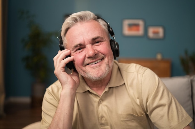 Retrato de un hombre feliz con auriculares en las orejas un anciano se ríe a la cámara