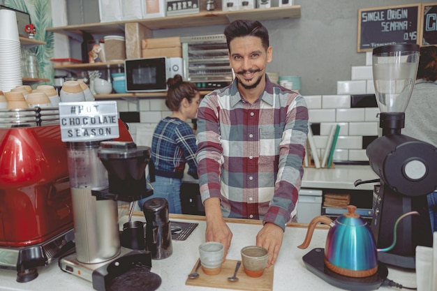 Retrato de hombre feliz barista sirviendo a los visitantes