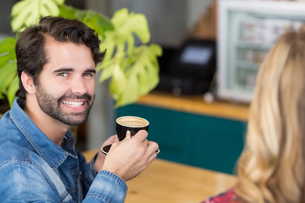 Retrato de hombre feliz bebiendo una taza de café en la cafetería