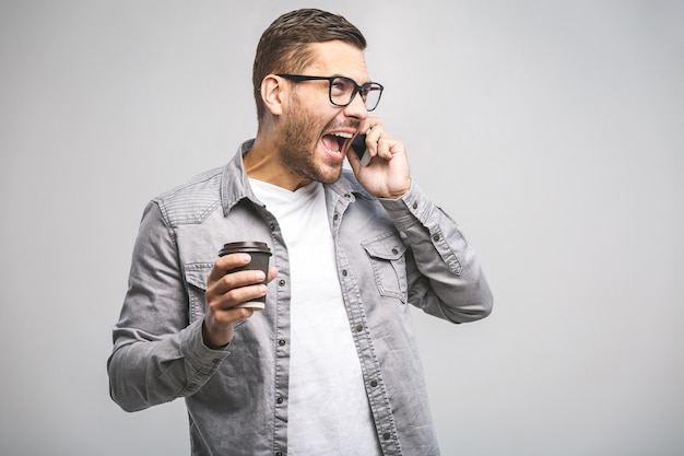 Retrato de un hombre feliz confía en sostener el teléfono móvil y celebrar el éxito aislado sobre fondo blanco.