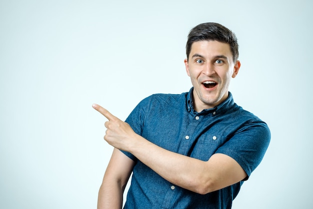 Retrato de un hombre feliz emocionado señalando con el dedo en el espacio de la copia