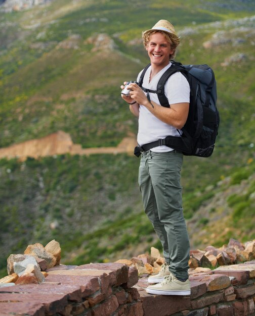 Foto retrato de hombre feliz y excursionista con binoculares y bolsa para visitas turísticas, viajes al aire libre o excursiones en la naturaleza joven hombre o turista con mochila de sombrero o herramienta óptica para el alcance de la vista o la exploración