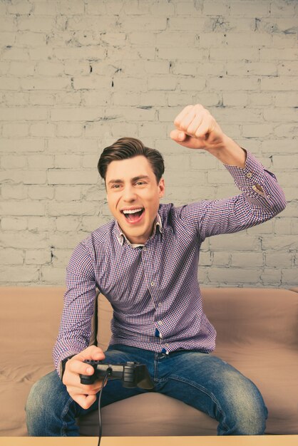 Foto retrato de hombre feliz ganando videojuegos con puño levantado