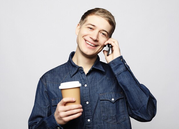 Retrato de hombre feliz hablando por teléfono y bebiendo café