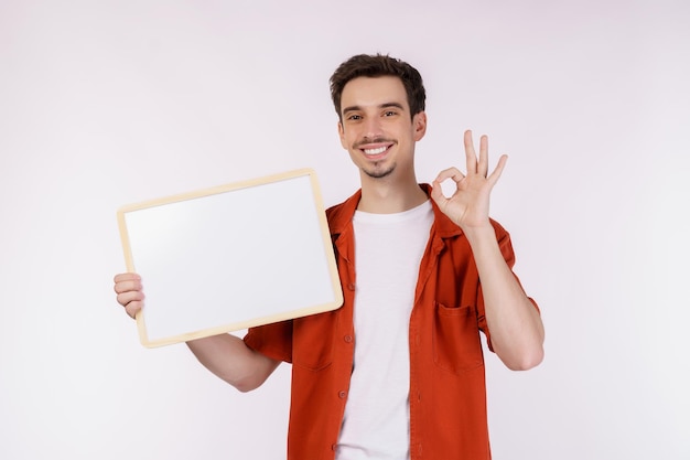 Retrato de hombre feliz mostrando letrero en blanco sobre fondo blanco aislado