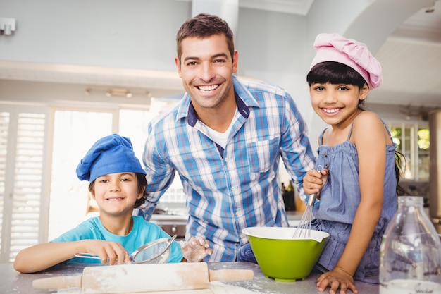 Retrato de hombre feliz con niños preparando comida