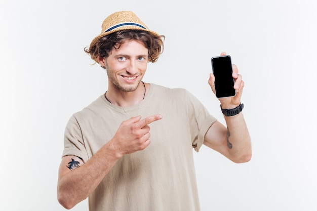 Retrato de un hombre feliz que señala el dedo en el teléfono inteligente con pantalla en blanco aislado en un fondo blanco.