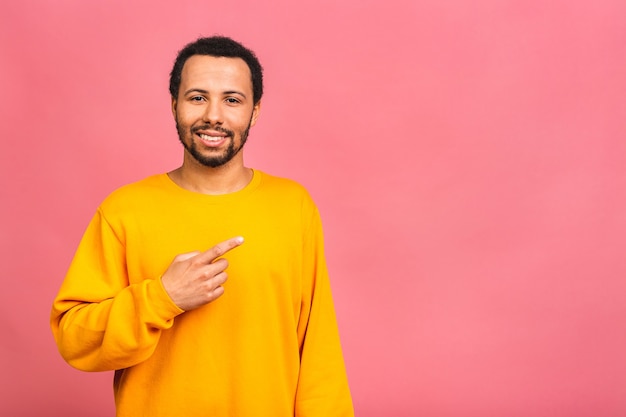 Retrato de un hombre feliz sonriente en casual apuntando con los dedos a un lado aislado sobre rosa.