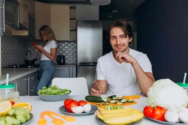 El retrato del hombre feliz en la tabla preparó la comida sana.