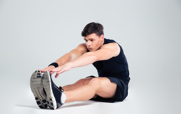 Retrato de un hombre fitness haciendo ejercicios de estiramiento aislado