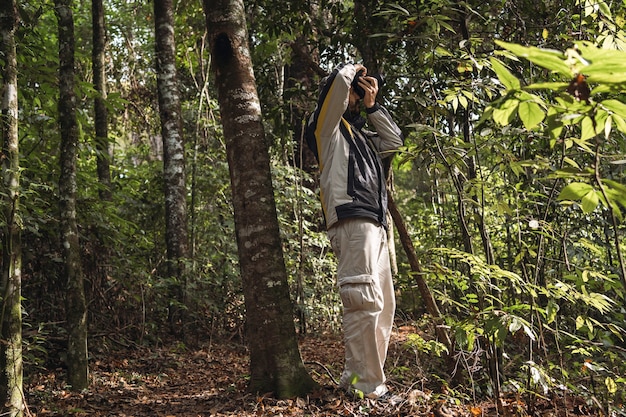 Retrato de un hombre fotografiando con su cámara en medio de la naturaleza.