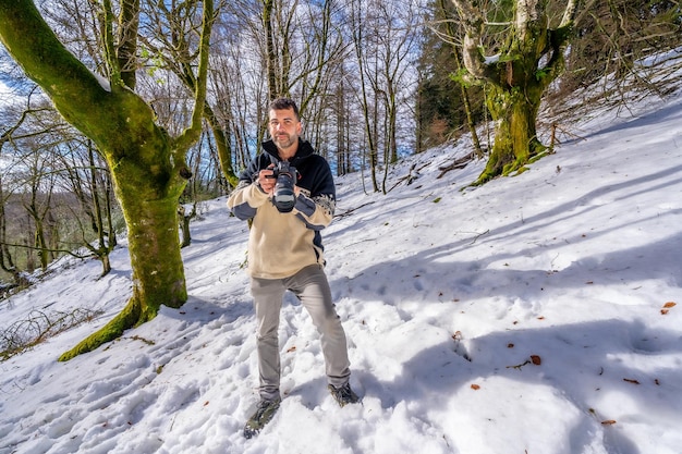 Retrato de un hombre fotógrafo en la nieve disfrutando de la fotografía de invierno en un bosque de hayas