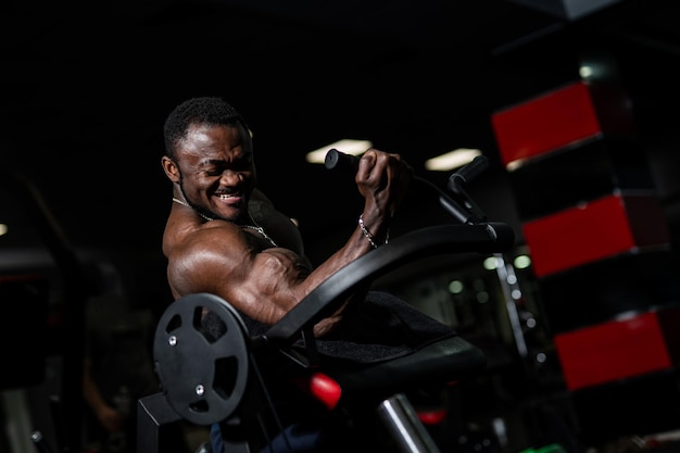 Un retrato de un hombre fuerte guapo caliente sin camisa sobre fondo oscuro. Foto en gimnasio. Concepto de belleza masculina. De cerca.