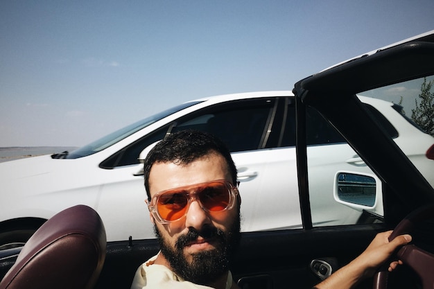 Retrato de un hombre con gafas de sol conduciendo un coche