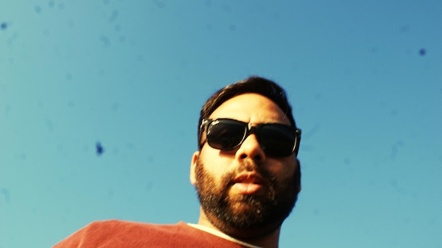 Foto retrato de un hombre con gafas de sol contra el cielo azul