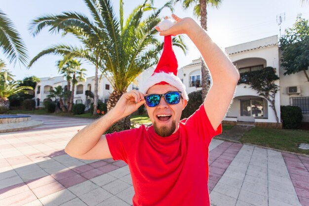 Foto retrato de un hombre con gafas de sol de pie junto a las palmeras