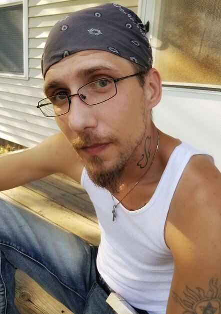 Foto retrato de un hombre con gafas y sombrero contra la casa