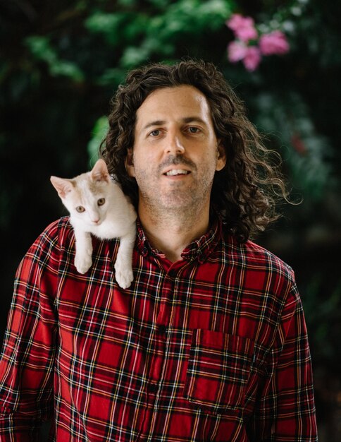 Foto retrato de un hombre con un gato en el hombro al aire libre