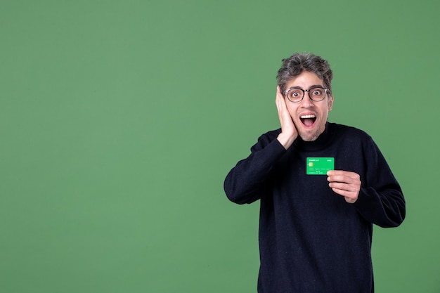 Retrato de hombre genio con tarjeta de crédito en foto de estudio pared verde