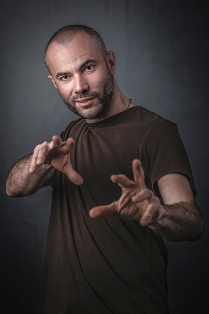 Foto retrato de un hombre gestando mientras está de pie contra un fondo gris