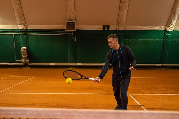 Retrato de un hombre golpeando una pelota de tenis en un partido en la cancha