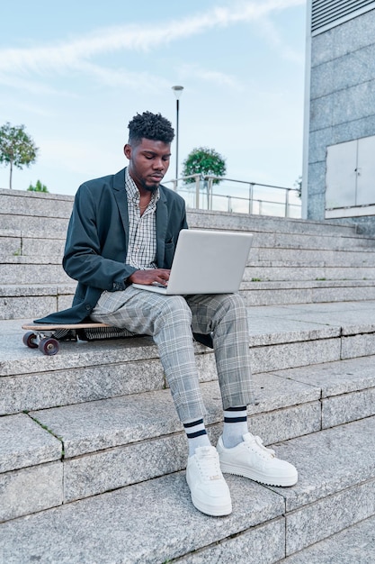 Retrato de un hombre guapo afroamericano con ropa informal sentado usando una computadora portátil para una reunión en línea videollamada videoconferencia Comunicación en línea con colegas Educación en línea trabajo remoto