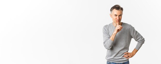 Retrato de hombre guapo astuto con cabello gris silenciando y sonriendo diciendo secreto preparar sorpresa