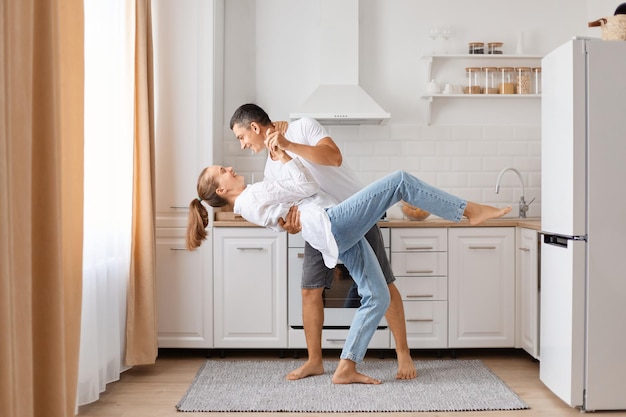 Retrato de un hombre guapo y una atractiva joven adulta caucásica divirtiéndose juntos mientras cocinan en la cocina una pareja romántica baila en casa