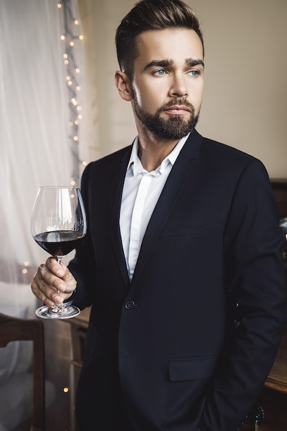 Retrato de hombre guapo con barba con una copa de vino tinto