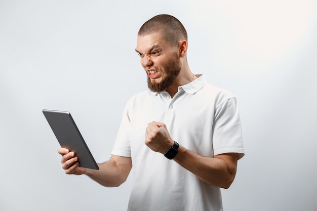 Retrato de un hombre guapo con barba feliz en una camiseta blanca con una tableta en blanco