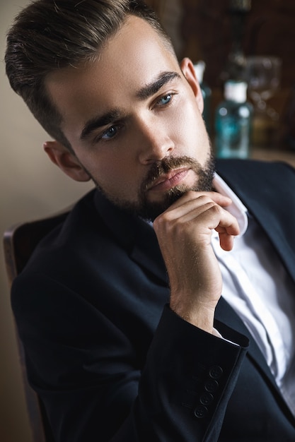 Retrato de hombre guapo con barba vestido con traje clásico negro